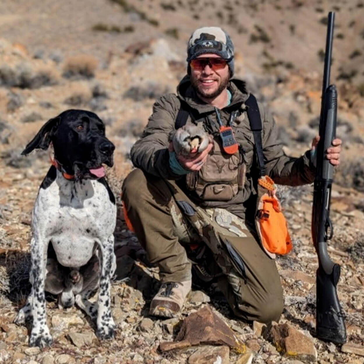 A Utah bird hunter kneels with his pointer.