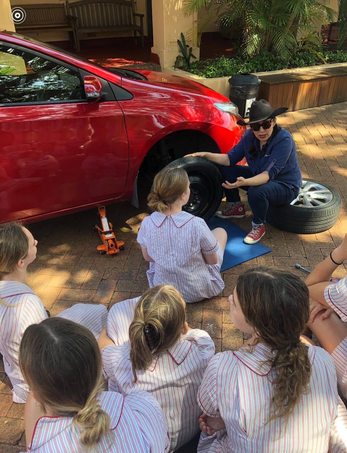 Girls learning how to change tires at Stella Maris College